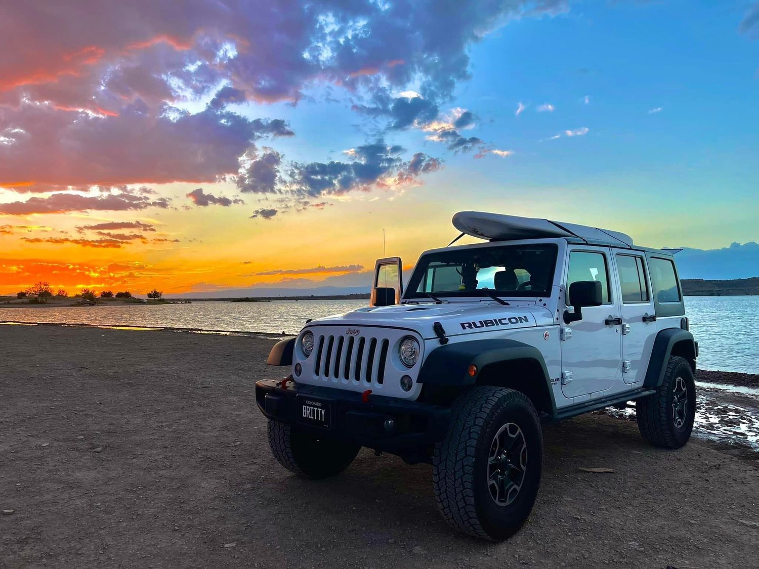 Paddleboard and Jeep beside a lake at sunset